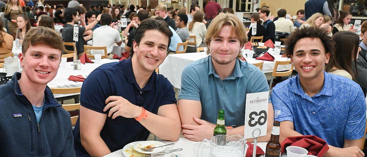 Four students pose at the dinner table for a photo.